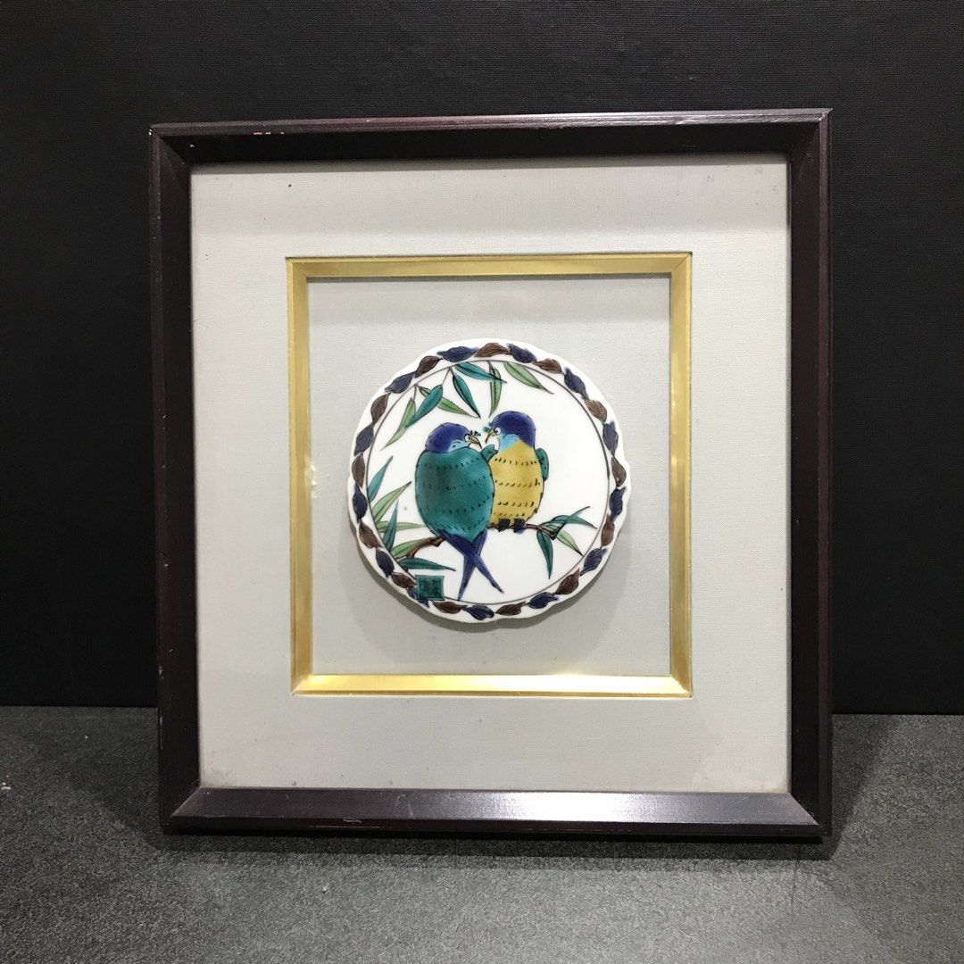 Framed Ceramic Art Tile with Lovebirds Design (Category: Frames & Pictures) located in Baao. Submitted by all.things.japan (Listing ID 1468747638, Image 1). Description: 11.0 x 10.25 x 1.35 inches - Artwork: Round ceramic tile depicting two colorful birds on bamboo branches with floral border - Framing: Deep square wooden frame with visible wood grain, fabric matting, and gold inner trim - Display: Includes hanging hardware for wall mounting or c