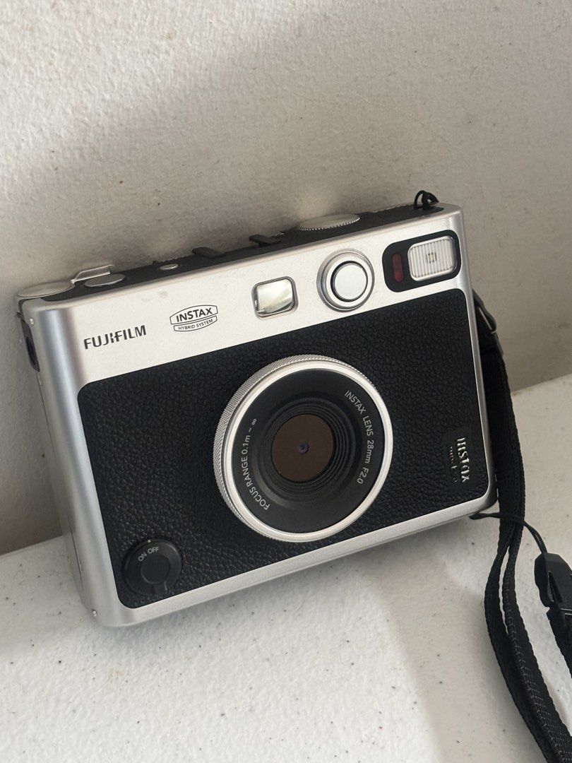 Fujifilm Instax Mini Evo Hybrid Instant Camera (Category: Cameras) located in Dasmarinas. Submitted by bykarla (Listing ID 1468733935, Image 2). Description: - Model: Fujifilm Instax Mini Evo (Silver & Black) - Condition: Clean body, minimal signs of handling, fully functional - Features: Hybrid digital & instant print, creative lens/film effects via dials, rear LCD screen with manual print lever - Inclusions: Black neck strap - Status: Ready for