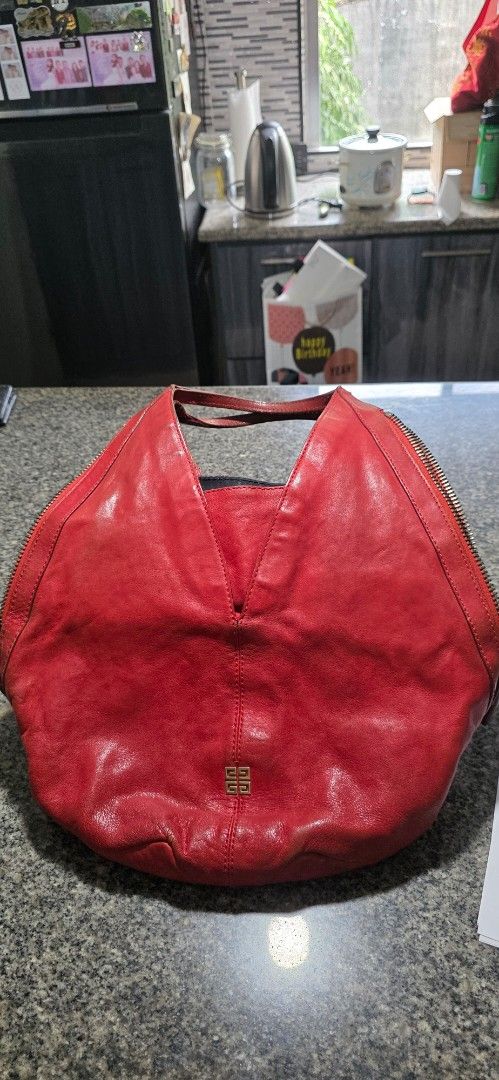 Givenchy Red Leather Shoulder Bag Handbag (Category: Luxury Bags & Wallets) located in Pasig City. Submitted by cspbt (Listing ID 1468733536, Image 1). Description: - Brand: Givenchy - Color: Bright red - Material: Soft leather with normal handling creases - Design: Slouchy shape with wraparound zipper and small gold logo emblem - Straps: Secure double shoulder straps - Interior: Black fabric lining with plenty of space for daily essentials - Aut