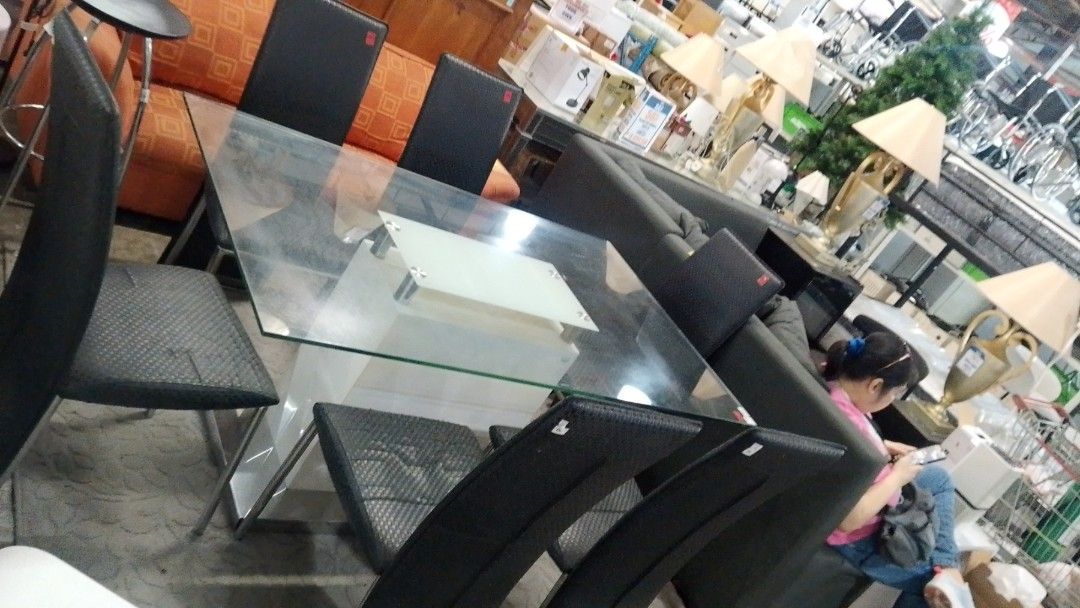 Glass Dining Table with Six Black Chairs (Category: Tables & Sets) located in Manila. Submitted by jlyn14 (Listing ID 1468780669, Image 1). Description: - Modern 6-seater dining set (table and chairs included) - Rectangular glass top with a sturdy white base - Six high-backed chairs in textured black upholstery - Ideal for dining rooms or kitchen spaces - Note: Minor smudges on the glass surface from display - Selling strictly as a complete set.