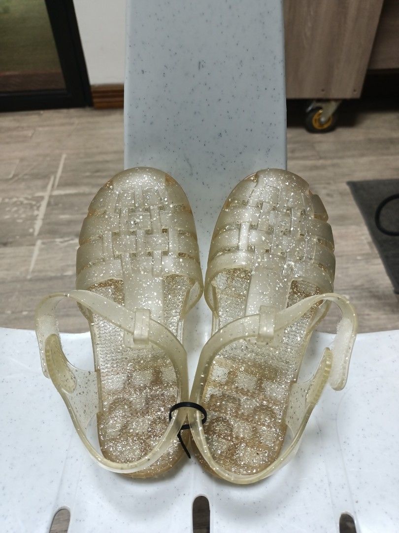 Glitter Jelly Sandals Size 28 (Category: Babies & Kids Fashion) located in Santa Maria. Submitted by anne_s.list (Listing ID 1468796248, Image 1). Description: - Color/Style: Clear gold with glitter, closed-toe woven design - Size: 28 (17.5 -18.5 cm) - Closure: Adjustable ankle strap with buckle - Sole: Textured with molded patterns for better grip - Origin: Made in Spain - Ideal for: Summer, beach trips, and everyday casual wear.