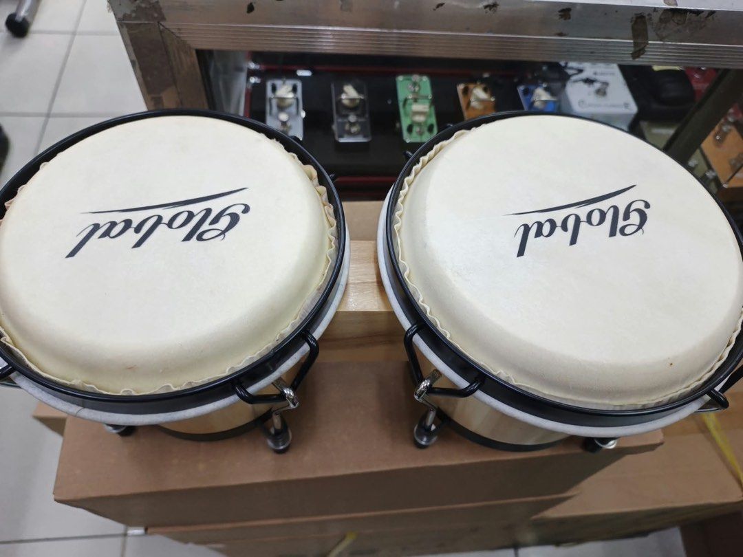 Global Wood Bongo Drums (Category: Musical Instruments) located in Las Pinas. Submitted by andreadomingo2518 (Listing ID 1468767125, Image 3). Description: - Product: Global bongo drums with dual drum setup connected by a wooden block - Finish: Natural wood finish with clean surfaces - Hardware: Black metal hardware, rims, and standard tuning lugs - Drum Heads: White drum heads featuring a clear brand logo - Condition: Ready to play.