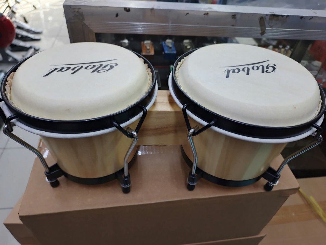 Global Wood Bongo Drums (Category: Musical Instruments) located in Las Pinas. Submitted by andreadomingo2518 (Listing ID 1468767125, Image 2). Description: - Product: Global bongo drums with dual drum setup connected by a wooden block - Finish: Natural wood finish with clean surfaces - Hardware: Black metal hardware, rims, and standard tuning lugs - Drum Heads: White drum heads featuring a clear brand logo - Condition: Ready to play.