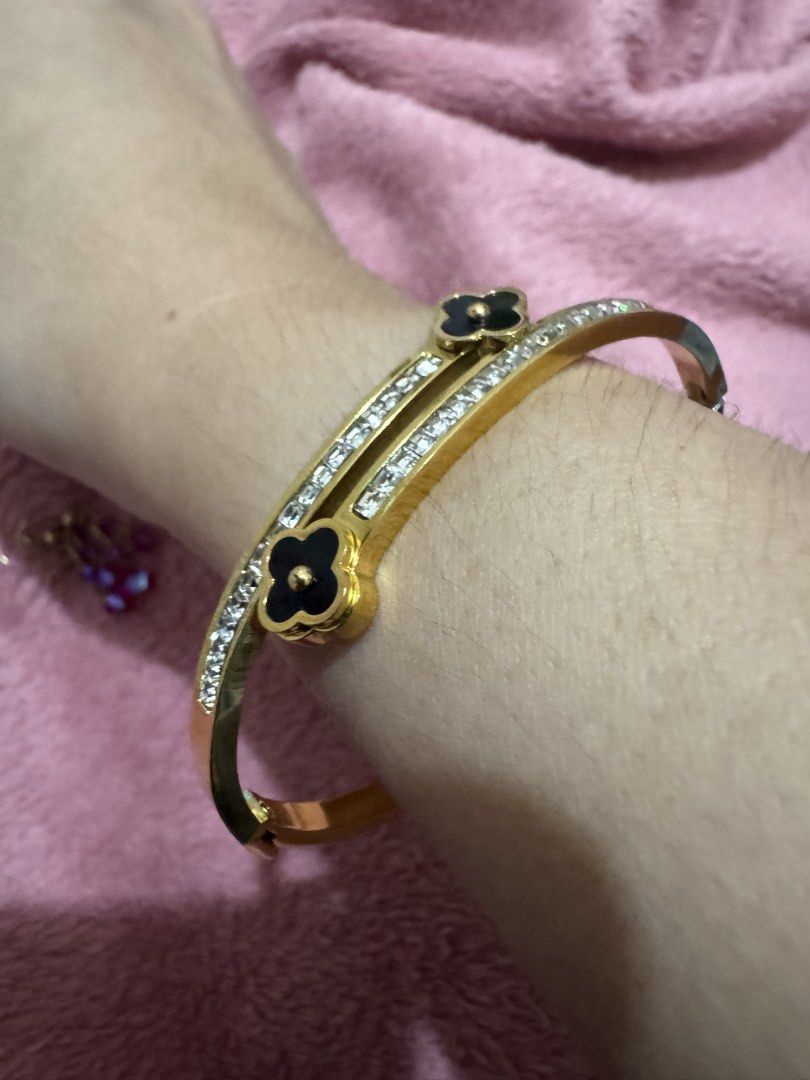 Gold Clover Bangle Bracelet with Rhinestones (Category: Bracelets) located in Angeles City. Submitted by thala.1204.68 (Listing ID 1468765715, Image 1). Description: - Gold-tone double band bangle bracelet - Features double rows of sparkly rhinestones - Elegant black clover charms with a small gold ball center at each end - Convenient hinged clasp closure on the side for easy wear - Versatile statement piece for daily use or dressing up.