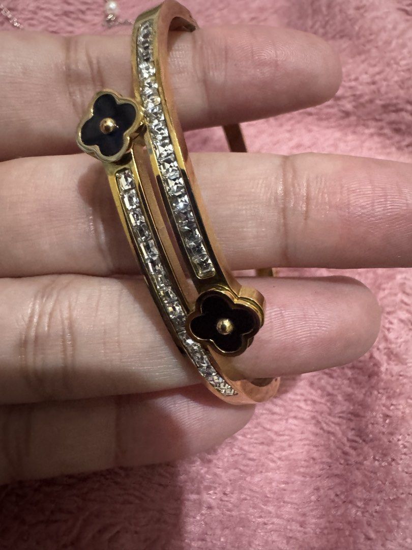 Gold Clover Bangle Bracelet with Rhinestones (Category: Bracelets) located in Angeles City. Submitted by thala.1204.68 (Listing ID 1468765715, Image 3). Description: - Gold-tone double band bangle bracelet - Features double rows of sparkly rhinestones - Elegant black clover charms with a small gold ball center at each end - Convenient hinged clasp closure on the side for easy wear - Versatile statement piece for daily use or dressing up.