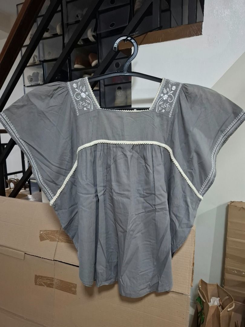 Gray Embroidered Flutter-Sleeve Blouse (Category: Blouses) located in Pasig City. Submitted by dripcounty (Listing ID 1468839328, Image 1). Description: Gray Embroidered Flutter-Sleeve Blouse ₱180 Size: Unconfirmed — please confirm in chat Condition: Preloved; please check actual photos Gray blouse with white embroidery, decorative trim, square neckline and flutter sleeves. Actual item shown in photos. Delivery fee shouldered by buyer (Lalamove /