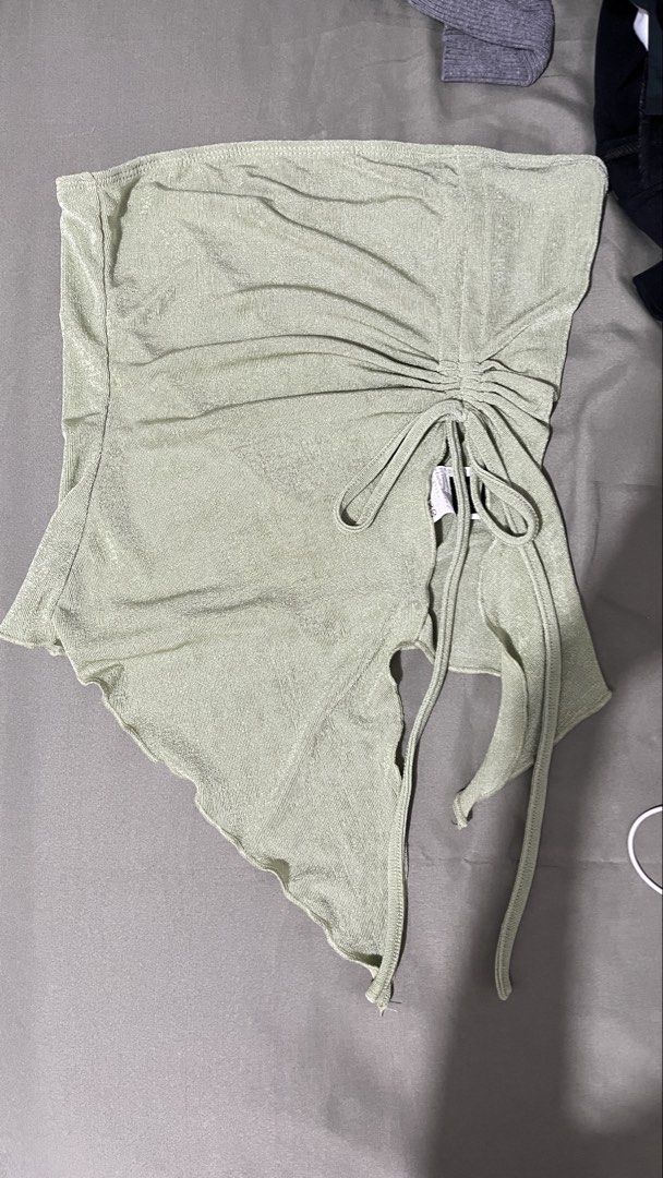 green ruched asymmetrical hem tube top (Category: Sleeveless) located in Cebu City. Submitted by minymal (Listing ID 1468897874, Image 1). Description: - Color: Sage green with a subtle shimmer texture - Design: Ruched side with adjustable drawstring ties and trendy asymmetrical pointed hem - Fabric: Lightweight and stretchy for a comfortable fit - Versatility: Easy to style with high-waisted denim, shorts, or skirts - Occasion: Perfect for casua