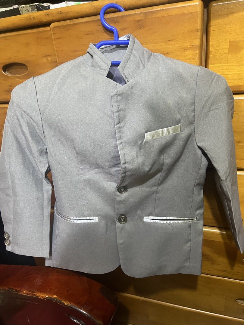 Grey Boys Mandarin Collar Suit Jacket (Category: Coats, Jackets and Outerwear) located in Carmona. Submitted by tonette95 (Listing ID 1468777780, Image 2). Description: - Color: Grey - Style: Mandarin collar with two-button closure - Pockets: One chest pocket and two lower pockets with shiny silver trim - Details: Cuff buttons on sleeves, structured shoulders, and tailored fit - Condition: Clean fabric throughout Ginamit lang ng kasal. Isang bese