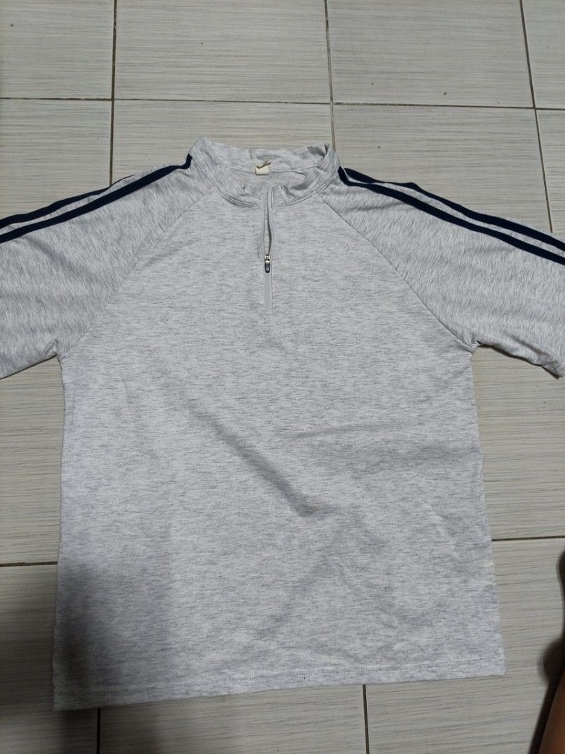 Grey half zip t-shirt with navy stripes (Category: Tshirts & Polo Shirts ) located in Manila. Submitted by puredeer_0057a7 (Listing ID 1468817784, Image 1). Description: - Style: Athletic tee with short front zip and stand-up collar - Design: Grey marled fabric with dark blue stripes on raglan sleeves - Material: Comfortable, activewear-friendly material - Condition: Clean and well-maintained with no obvious flaws.