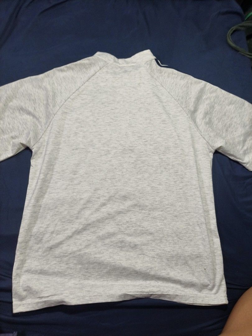 Grey half zip t-shirt with navy stripes (Category: Tshirts & Polo Shirts ) located in Manila. Submitted by puredeer_0057a7 (Listing ID 1468817784, Image 2). Description: - Style: Athletic tee with short front zip and stand-up collar - Design: Grey marled fabric with dark blue stripes on raglan sleeves - Material: Comfortable, activewear-friendly material - Condition: Clean and well-maintained with no obvious flaws.