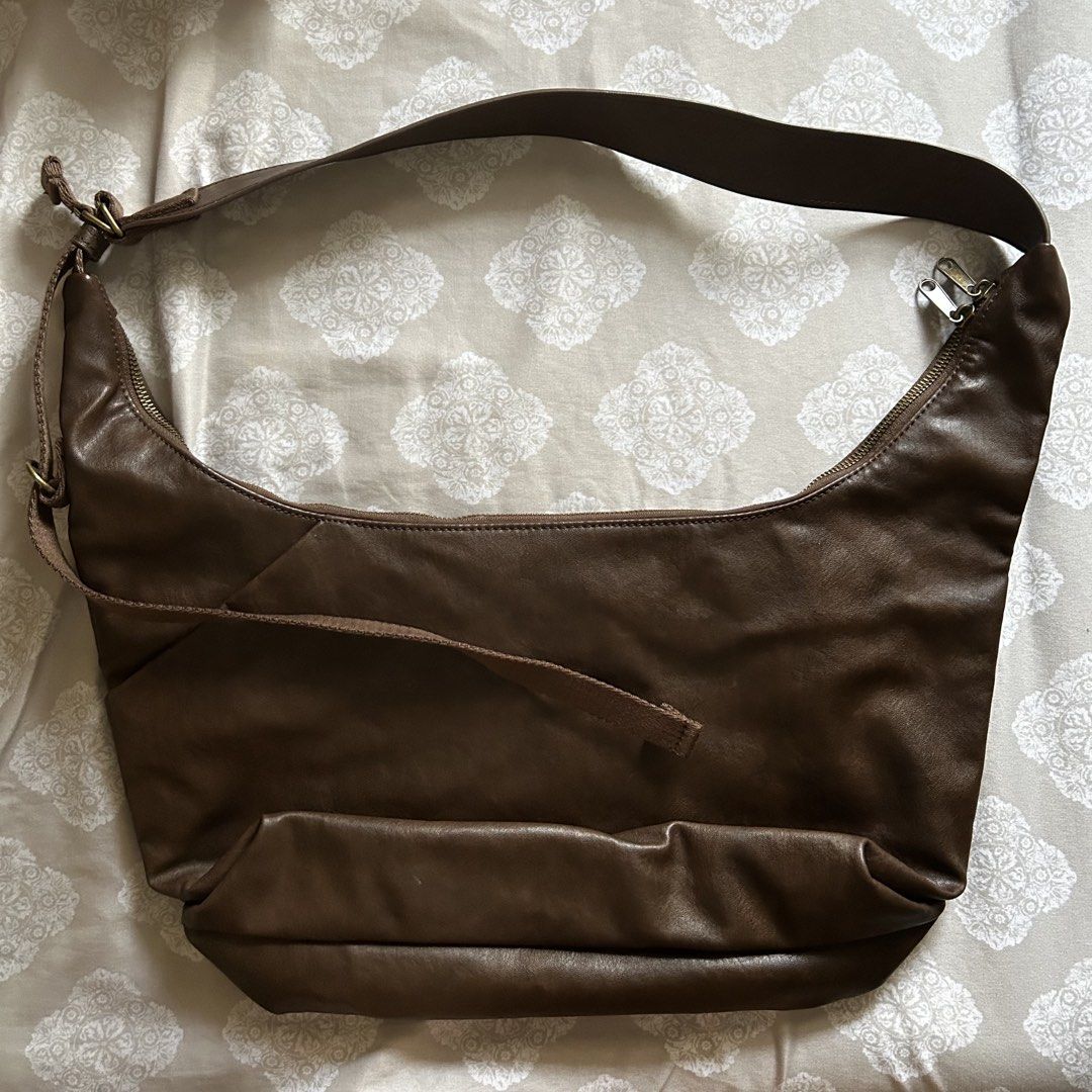 GU Brown shoulder bag (Category: Shoulder Bags) located in Marikina City. Submitted by ellies.mnl (Listing ID 1468754946, Image 2). Description: - Color & Material: Rich brown faux leather - Style: Slouchy hobo silhouette with a clean, minimalist look - Closure: Secure zip-top closure - Adjustability: Adjustable strap for a customized drop length - Structure: Flat structured bottom panel to maintain shape - Versatility: Ideal for casual outfits a