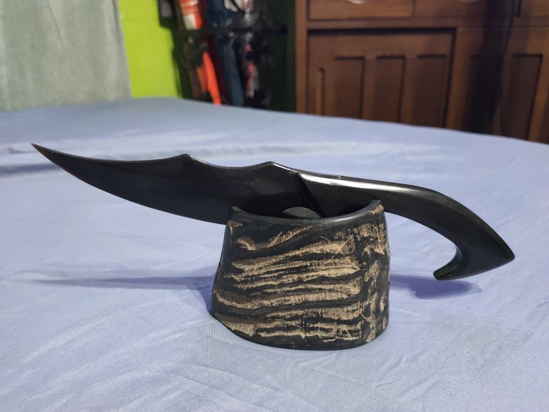 Handcrafted decorative horn dagger with stand (Category: Vintage Collectibles) located in Santa Maria. Submitted by bexsantiago (Listing ID 1468808962, Image 2). Description: - Unique decorative dagger crafted from genuine animal horn - Dark blade and handle with a sleek, polished finish - Includes a matching textured display stand made of horn - Solid build with smooth, elegant contours - Perfect statement piece for desks, shelves, or weapon col