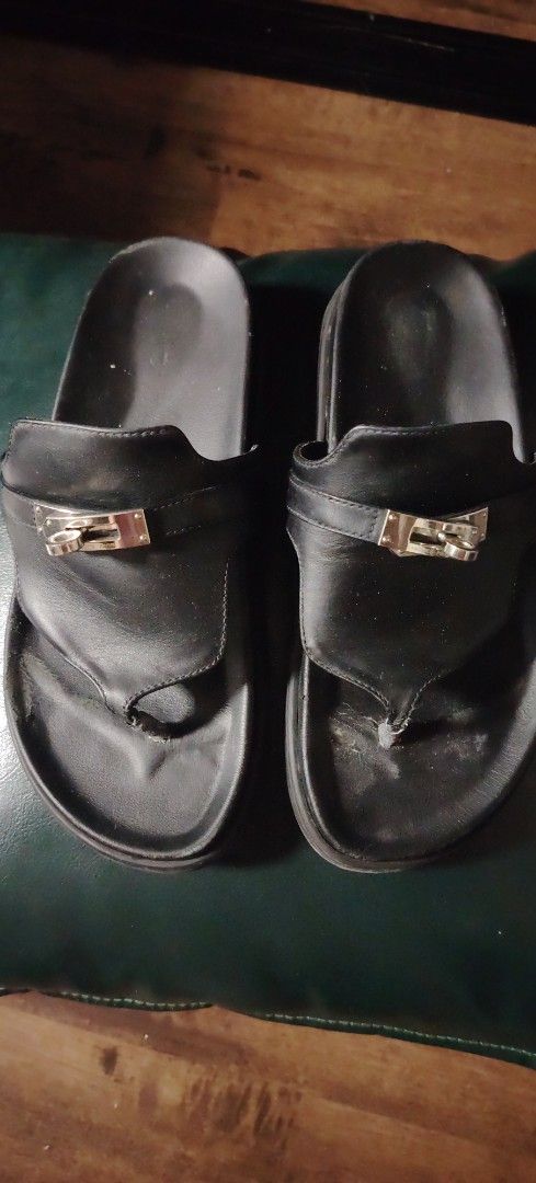 Hermes Black Leather Sandals With Kelly Hardware (Category: Flats & Sandals) located in Makati City. Submitted by cess2377 (Listing ID 1468808973, Image 1). Description: - Brand: Hermes - Style: Black leather thong sandals with slip-on design - Hardware: Iconic Kelly-style hardware engraved with "Hermes Paris" - Comfort: Cushioned footbed for all-day wear - Details: Signature patterned sole with Hermes and "Made in Italy" stamps - Condition: Sign