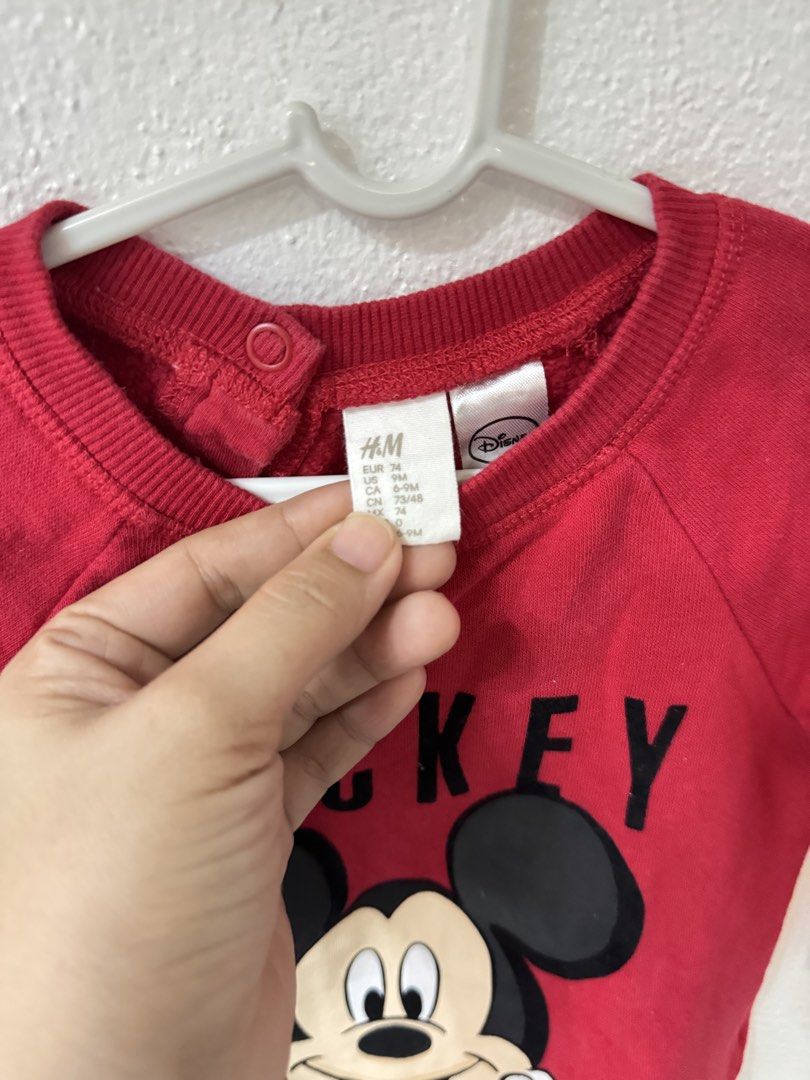 H&M Disney Mickey Mouse Red Sweatshirt 6-9M (Category: Babies & Kids Fashion) located in Manila. Submitted by janelica220598 (Listing ID 1468820968, Image 2). Description: - Brand: H&M - Design: Red Mickey Mouse graphic with bold black lettering - Size: 6-9 months (EUR 74) - Material: Soft cotton blend, ideal for cooler weather - Feature: Shoulder snap buttons for easy dressing - Condition: Clean and well-maintained.