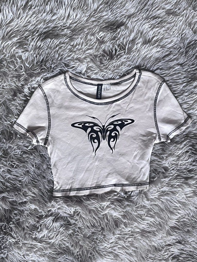 H&M Divided Butterfly Print Crop Top (Category: Shirts) located in Quezon City. Submitted by toasterpiee (Listing ID 1468883094, Image 1). Description: - Brand: H&M Divided - Color/Style: White short sleeve crop top - Design: Black tribal butterfly graphic on the front - Details: Contrast black overlock stitching on neckline, sleeves, shoulders, and hem - Material: Soft stretch cotton fabric - Fit: Comfortable crew neck and cropped length.