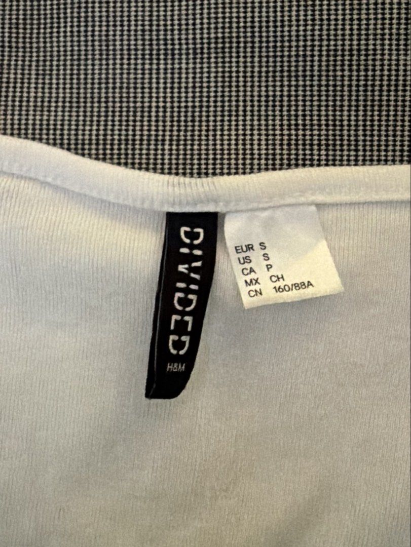 H&M Divided White Button Front Crop Top Size S (Category: Shirts) located in Manila. Submitted by jaehyun2829 (Listing ID 1468777085, Image 1). Description: - Brand: H&M Divided - Size: S (EUR S, US S) - Color: White - Material: Stretchy ribbed knit fabric - Design: Scoop neckline, short sleeves with lettuce hem, and front button placket - Condition: Great basic piece, perfect for layering or wearing with high-waisted denim.