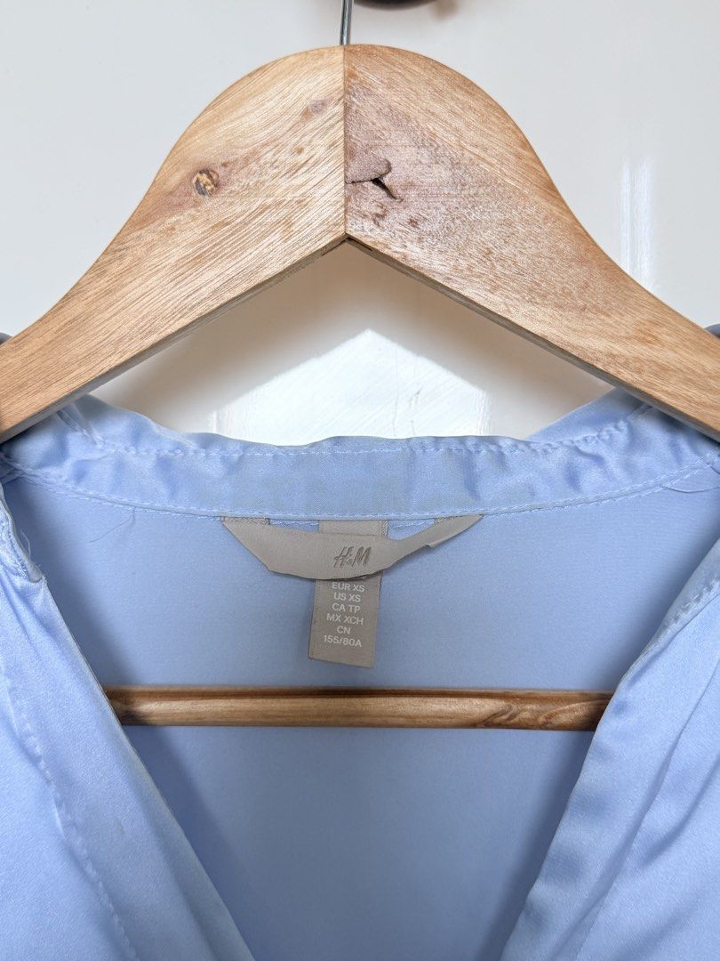 H&M Light Blue Satin Blouse Size XS (Category: Blouses) located in Quezon City. Submitted by ynnapenyaranda (Listing ID 1468870358, Image 2). Description: - Brand: H&M - Item: Light blue satin blouse - Size: XS - Features: V-neck collar, long sleeves with button cuffs, curved high-low hem - Finish: Smooth and shiny - Condition: Great, clean with no flaws.