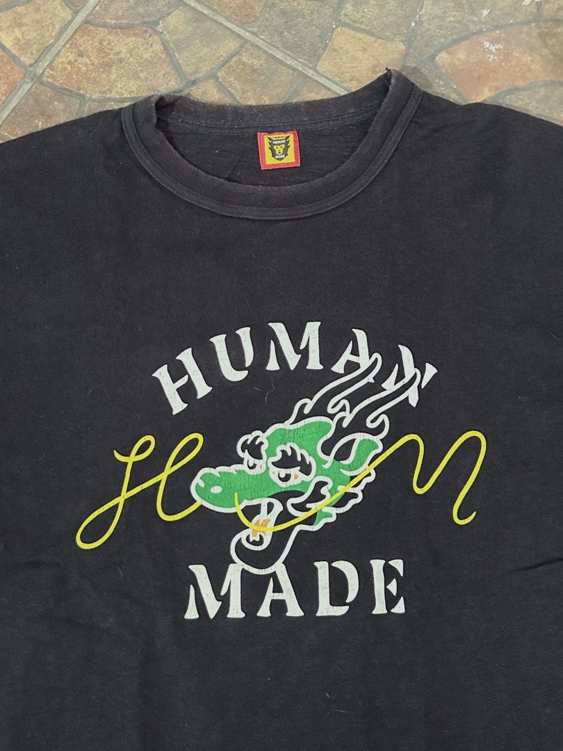 Human Made Dragon Graphic Black T-Shirt (Category: Tshirts & Polo Shirts ) located in Imus. Submitted by mikeythrifts (Listing ID 1468841473, Image 2). Description: - Brand: Human Made - Style: Short sleeve crewneck t-shirt (Regular fit) - Dimes: 20.5 x 27.5 - Design: Large green and white dragon front graphic with white lettering and yellow script - Details: Yellow brand logo tag on the inner collar - Material: Cotton - Condition: Good, with lig
