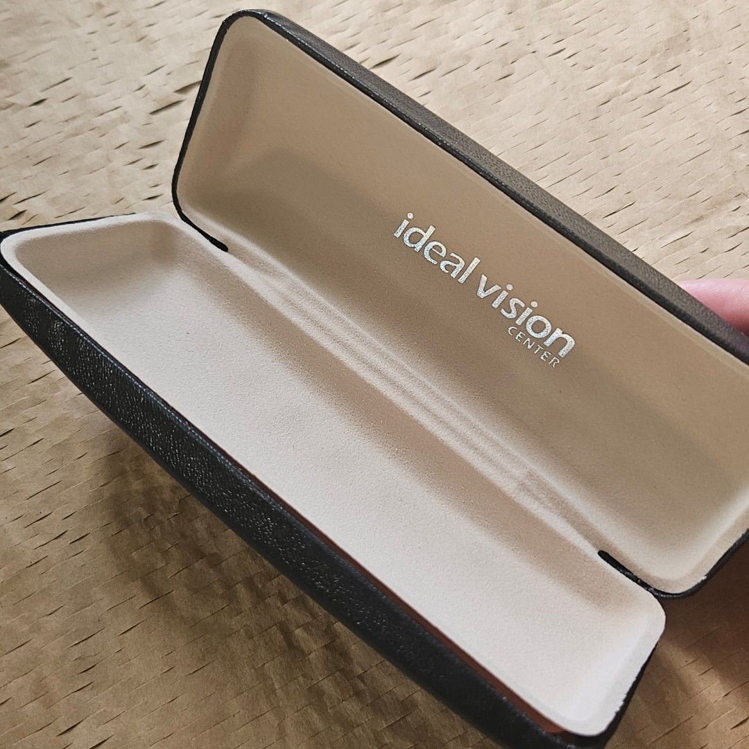 Ideal Vision Center black hard eyeglasses case (Category: Sunglasses & Eyewear) located in Imus. Submitted by a.niko (Listing ID 1468755780, Image 1). Description: - Brand: Ideal Vision Center - Color: Black with cream interior - Exterior: Textured faux leather with debossed logo - Interior: Soft felt lining to prevent scratches - Closure: Sturdy snap closure for security - Use: Ideal daily accessory for bags and backpacks.