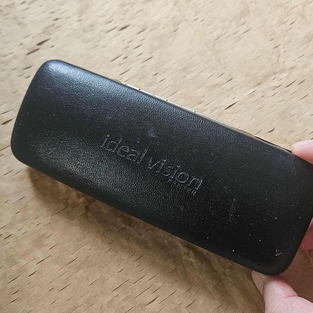 Ideal Vision Center black hard eyeglasses case (Category: Sunglasses & Eyewear) located in Imus. Submitted by a.niko (Listing ID 1468755780, Image 2). Description: - Brand: Ideal Vision Center - Color: Black with cream interior - Exterior: Textured faux leather with debossed logo - Interior: Soft felt lining to prevent scratches - Closure: Sturdy snap closure for security - Use: Ideal daily accessory for bags and backpacks.