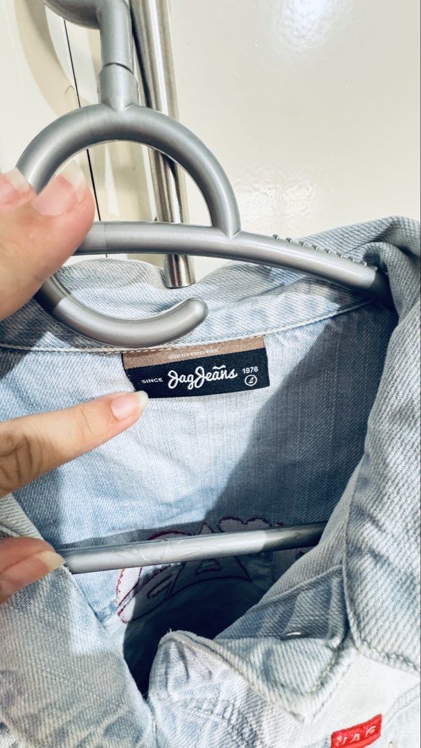 Jag Jeans Light Wash Denim Jacket Size L (Category: Coats, Jackets and Outerwear) located in Manila. Submitted by silentcrystal-26f2 (Listing ID 1468771608, Image 2). Description: - Brand: Jag Jeans (Est. 1976) - Size: Large - Color/Wash: Light wash denim - Design: Classic trucker style with button-up front and chest pockets - Special Detail: Bold red JAG logo embroidery with a pink heart on the back and signature red brand tag - Fit: Easy to lay