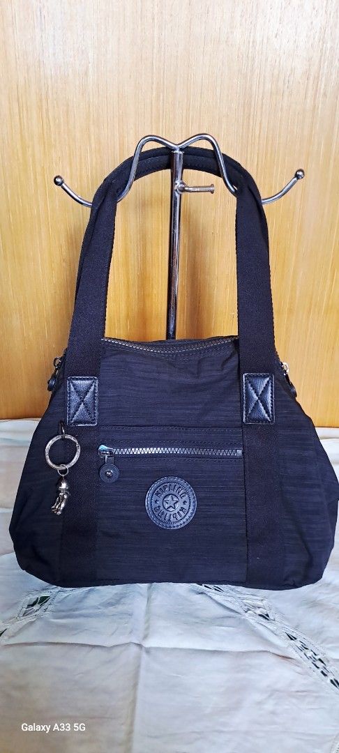 Kipling Black Nylon Tote Shoulder Bag with Strap (Category: Tote Bags) located in Baguio. Submitted by mng_assorted_baguio (Listing ID 1468787772, Image 3). Description: - Brand: Kipling - Material: Durable textured crinkle nylon in classic black - Carry options: Dual top handles and a detachable, adjustable shoulder strap - Pockets: Convenient front zip pocket with a spacious main compartment for daily essentials - Extras: Includes the iconic ro