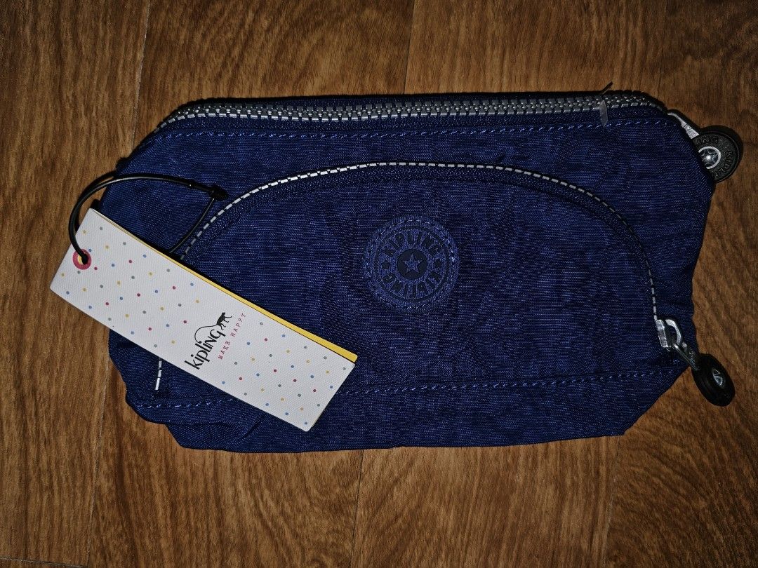 Kipling Blue Pouch Pencil Case (Category: Purses & Pouches) located in Quezon City. Submitted by findsbydavie (Listing ID 1468821695, Image 2). Description: - Brand: Kipling - Condition: Brand new with tags attached - Color: Deep blue with iconic round logo patch - Material: Durable textured nylon - Features: Multiple zippered compartments and built-in elastic pen holders - Details: Branded zipper pulls - Perfect for: Organizing stationery, makeu