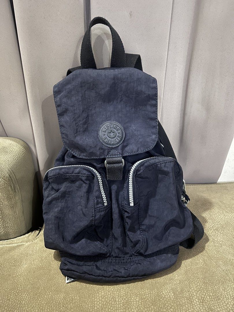 Kipling Navy Blue Nylon Backpack (Category: Backpacks) located in San Fernando. Submitted by WonderMamaonlineshop (Listing ID 1468892151, Image 1). Description: - Brand: Kipling - Color: Dark navy blue - Material: Nylon - Features: Front buckle, 2 front zip pockets with circular branded pull tabs, top handle, and adjustable shoulder straps - Condition: Excellent / Ready to use - Perfect for daily commute, school, or travel.