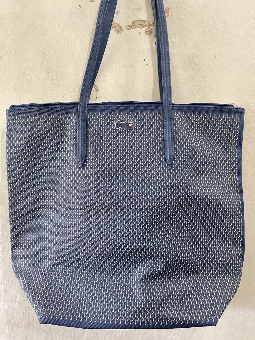 Lacoste Blue Patterned Tote Bag (Category: Tote Bags) located in Quezon City. Submitted by akismurabels (Listing ID 1468764616, Image 1). Description: AUTHENTIC Decluterring my personal items Size: L:39cm W: 15cm H:34cm Loc: Quezon City MOP: Gcash MOD: Lalamove PM if interested Slightly negotiable - Brand: Lacoste - Color: Classic Navy Blue - Material/Design: Unique textured exterior pattern with a clean, structured base - Straps: Comfortable thi