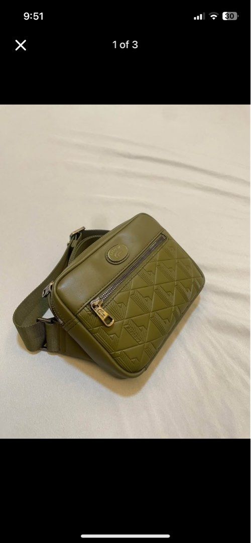 Lacoste Olive Green Crossbody Bag Monogram Pattern (Category: Cross-body Bags) located in Cebu City. Submitted by andrie_13 (Listing ID 1468783947, Image 2). Description: - Authentic green Lacoste crossbody bag in a stylish olive tone - Structured design with a textured geometric monogram front zipped pocket - Signature metal oval Lacoste logo badge near the top zipper - Durable and adjustable woven strap for a comfortable fit - Sleek dark hardwa