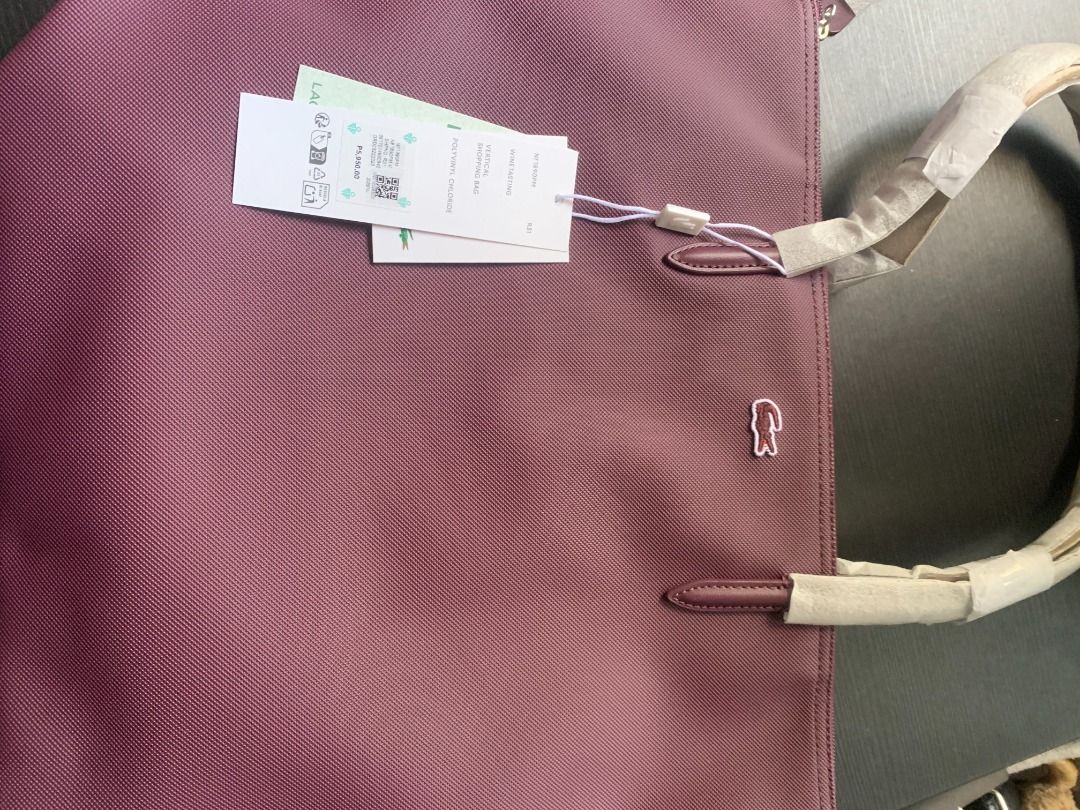 Lacoste Purple Tote Bag (Category: Tote Bags) located in Quezon City. Submitted by armicg (Listing ID 1468722572, Image 1). Description: - Brand new with original retail tags attached - Handles still wrapped in protective paper - Stylish purple textured fabric body with iconic crocodile logo - Spacious and roomy interior, perfect as an everyday carryall - 100% authentic Lacoste.