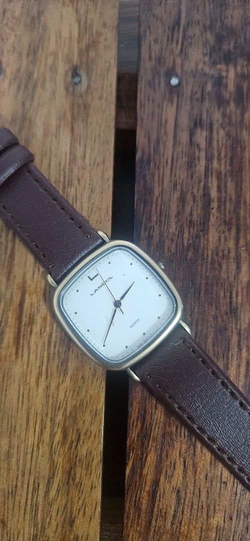 Lancel Quartz Watch with Brown Leather Strap (Category: Women's Watches) located in Santa Maria. Submitted by rommelmateo (Listing ID 1468860556, Image 1). Description: - Brand: Lancel - Movement: Battery-operated quartz - Case: Gold-tone square case with stainless steel back (Citizen movement base) - Dial: Clean white minimalist dial - Crown: Uniquely positioned on the left side - Strap: Brown leather strap - Condition: Vintage.