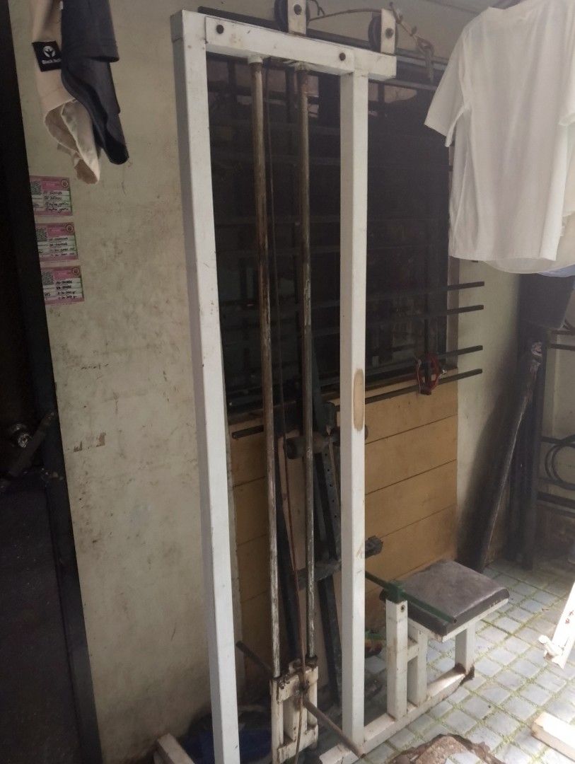 Lat pulldown home gym equipment with bench (Category: Cardio & Fitness Machines) located in Paranaque City. Submitted by jannaelise24 (Listing ID 1468789796, Image 3). Description: - Complete home gym setup featuring a sturdy white metal frame, vertical guide rods, cable attachment, and attached padded seat - Shows minor rust on metal parts and general wear from previous workouts, but fully functional - Heavy-duty fitness equipment ideal for gara
