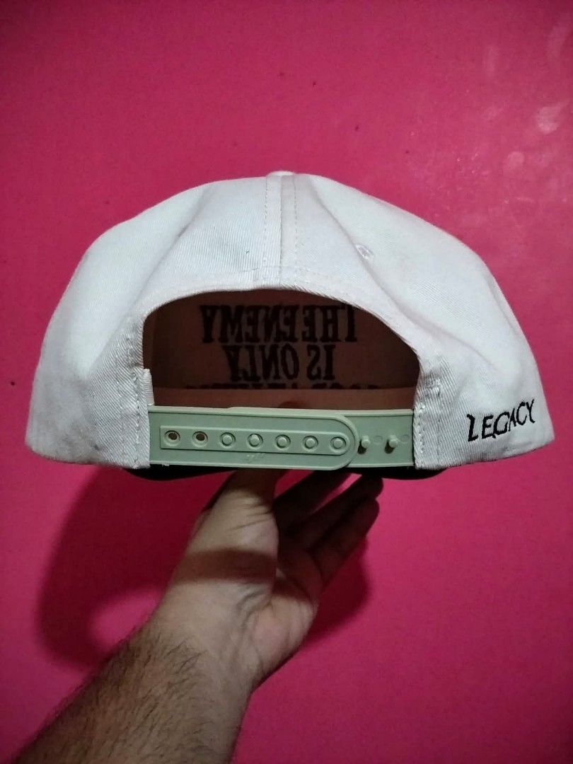 Legacy The Enemy Is Only Good At Lying Snapback Hat (Category: Caps & Hats) located in Mangaldan. Submitted by niftythrifty69 (Listing ID 1468730883, Image 2). Description: - Brand/Model: Legacy snapback hat - Colorway: White crown with contrasting black brim - Design: Bold embroidered front lettering "THE ENEMY IS ONLY GOOD AT LYING" and side branding - Closure: Adjustable green plastic snap closure - Details: Matching white taped seams and prin