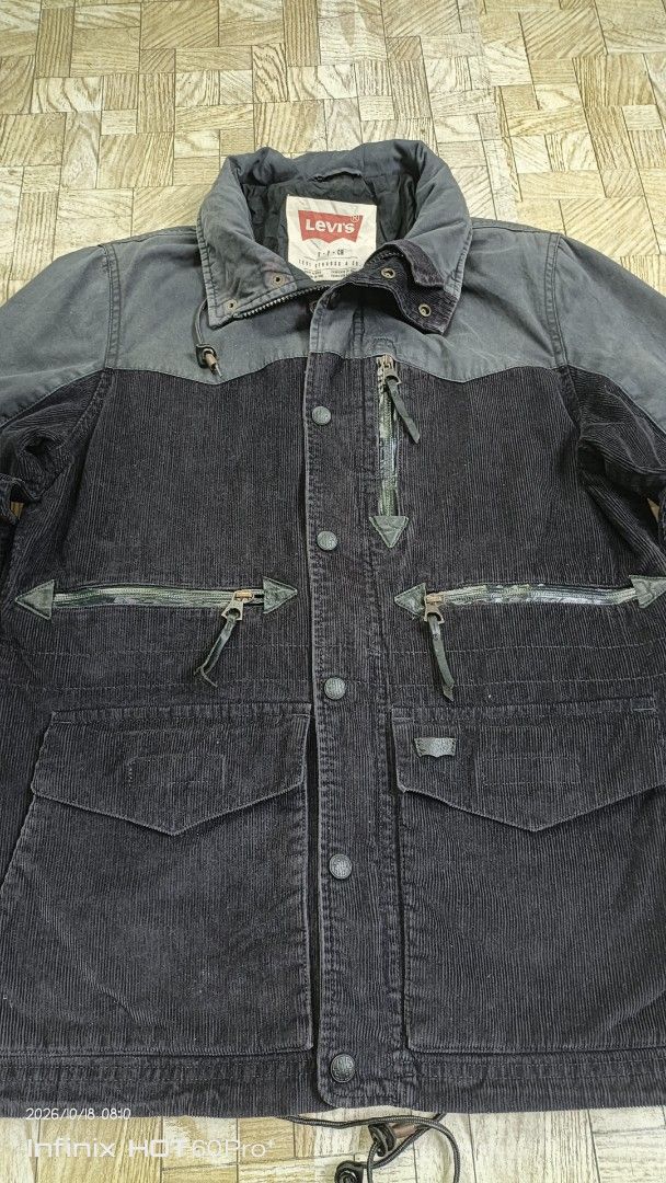 Levi's Corduroy Utility Jacket Grey Black (Category: Coats, Jackets and Outerwear) located in Candaba. Submitted by treblig. (Listing ID 1468713547, Image 2). Description: - Brand: Levi's - Material: Corduroy - Color: Grey and dark tones - Pockets: Multiple zippered front pockets - Details: Logo-stamped snap buttons, structured collar with inner red Levi's label - Fit & Adjustments: Adjustable drawstring hem and velcro cuffs.