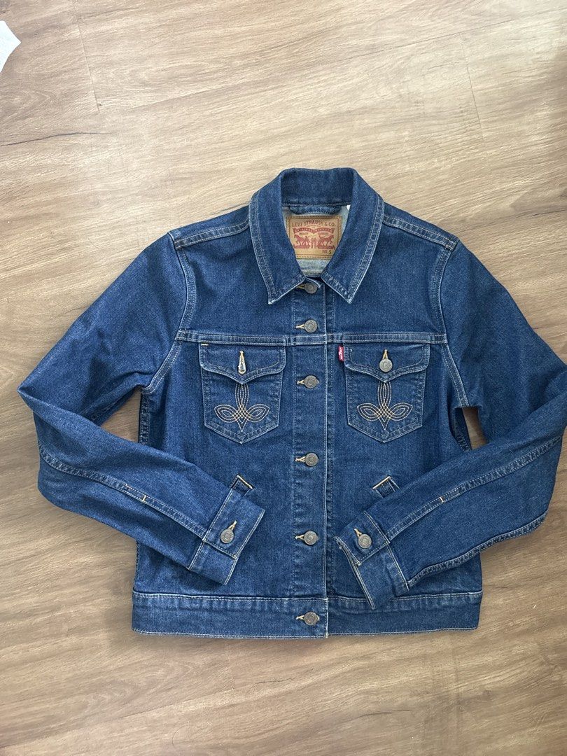 Levi's Denim Jacket Size S (Category: Coats, Jackets and Outerwear) located in Manila. Submitted by ysballsz (Listing ID 1468809290, Image 2). Description: - Brand: Levi's - Style: Classic denim jacket with dark blue wash - Size: S (fits true to standard sizing) - Details: Button-up front, metallic hardware, classic collar - Pockets: Dual chest pockets with button closures and intricate contrast embroidery - Branding: Iconic red Levi's tab on the