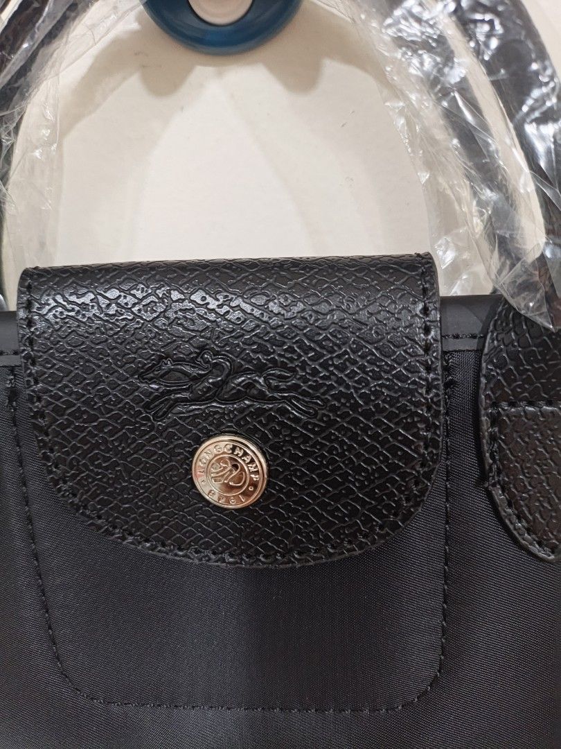 Longchamp Black Nylon Handbag with sling (Category: Luxury Bags & Wallets) located in Quezon City. Submitted by closeta38 (Listing ID 1468725058, Image 2). Description: - Brand: Longchamp - Material: Durable black nylon with genuine leather flap and handles - Condition: Brand new, handles still wrapped in original plastic - Hardware: Silver-tone with iconic horse logo snap button - Features: Lightweight, minimalist design with a spacious interior