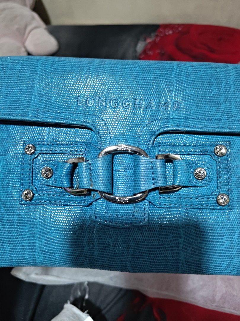 Longchamp Blue Lizard Texture Clutch Bag with Wrist Strap (Category: Luxury Bags & Wallets) located in Valenzuela. Submitted by wisewhale_46982b (Listing ID 1468779832, Image 2). Description: - Brand: Longchamp - Color: Bright blue with a chic lizard-texture finish - Hardware: Silver-tone decorative buckle, ring details, and sparkling rhinestone studs - Convenience: Matching blue wrist strap attached on the side - Interior: Signature blue branded