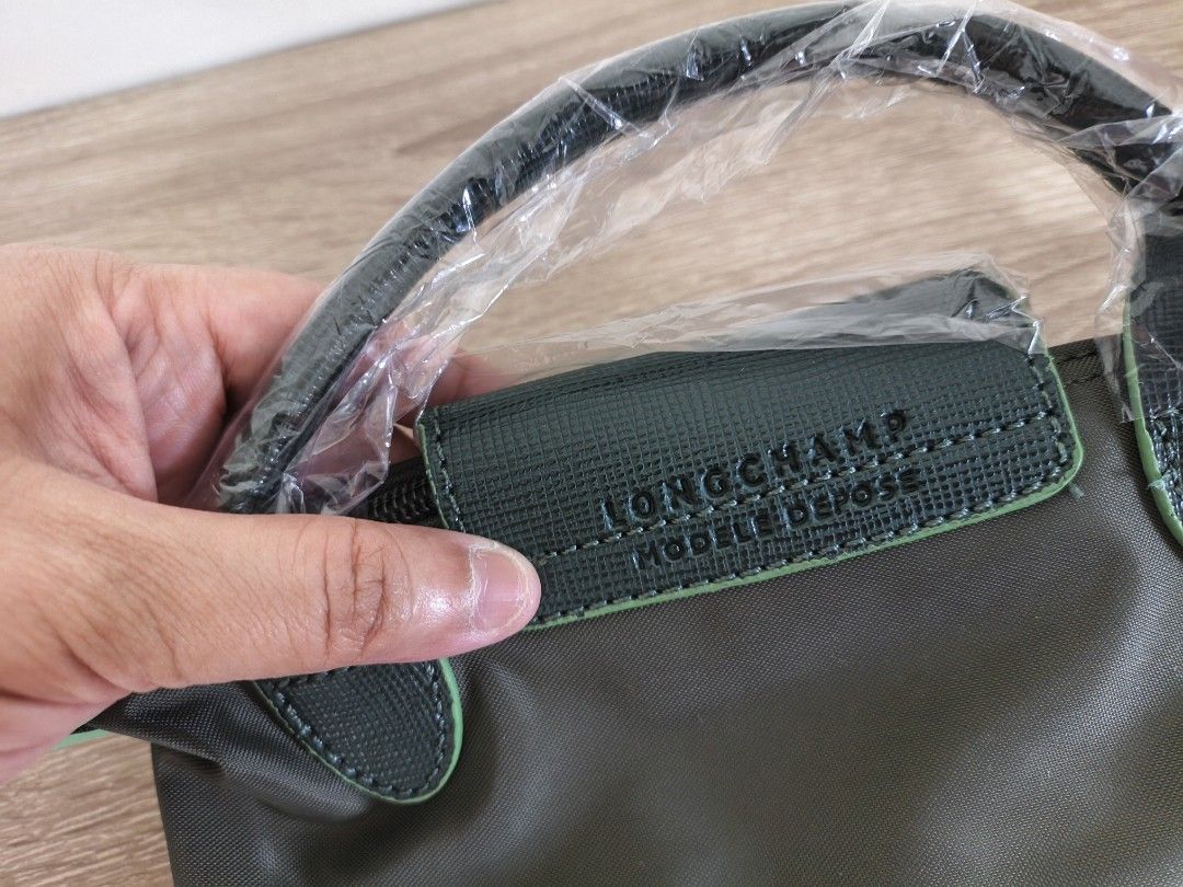 Longchamp Green Nylon Mini Top Handle Bag (Category: Luxury Bags & Wallets) located in Quezon City. Submitted by closeta38 (Listing ID 1468725165, Image 2). Description: - Brand: Longchamp - Color: Olive green nylon with dark green leather flap, handles, and strap - Condition: Brand new (handles still wrapped in protective plastic) - Hardware: Silver-tone with round metal zipper pull - Features: Iconic embroidered horse logo, secure zip closure, 
