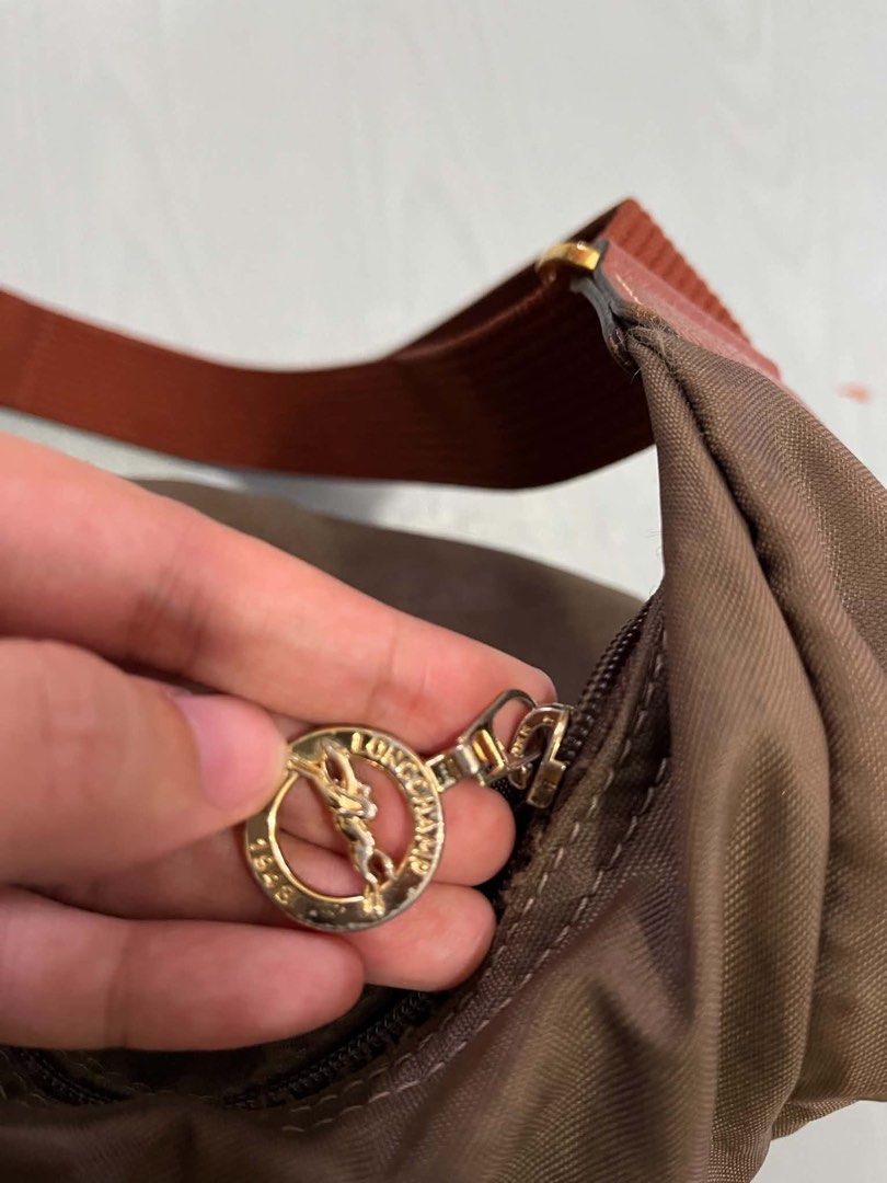 Longchamp Messenger Brown Nylon Hobo Shoulder Bag (Category: Luxury Bags & Wallets) located in Malita. Submitted by happy_duckling (Listing ID 1468873728, Image 2). Description: - Color: Brown nylon body with reddish-brown adjustable strap - Hardware: Gold-tone hardware with branded logo zipper pull - Pockets: Small exterior snap-flap pocket, interior zip pocket, and open slip pockets - Condition: Clean inside and out - Capacity: Large Size. Comf