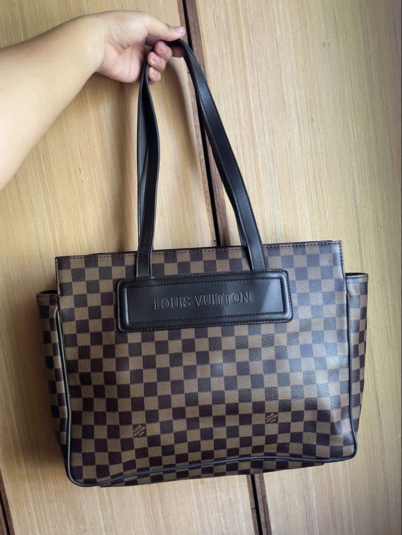 Louis Vuitton Damier Ebene Tote Bag (Category: Luxury Bags & Wallets) located in Pasuquin. Submitted by licashop.ph (Listing ID 1468731583, Image 1). Description: - Brown and black check pattern canvas tote - Structured leather handles and embossed Louis Vuitton front patch - Bright red interior lining with zipped pocket and D-ring attachment - Gold-tone hardware featuring LV logo zipper pull - Inside leather tag stamped Louis Vuitton Paris Made 
