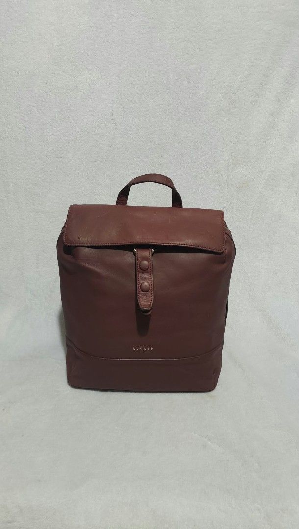 LOVCAT Leather Backpack Dark Red (Category: Backpacks) located in Bulacan. Submitted by georgiaapparel (Listing ID 1468890106, Image 2). Description: - Brand: LOVCAT - Color: Dark red - Material: Smooth leather finish - Closure: Flap front with secure snap button - Accessibility: Convenient side zipper access to the main compartment - Comfort: Adjustable shoulder straps and sturdy top handle - Condition: Excellent/Well-maintained - Best for: Dail