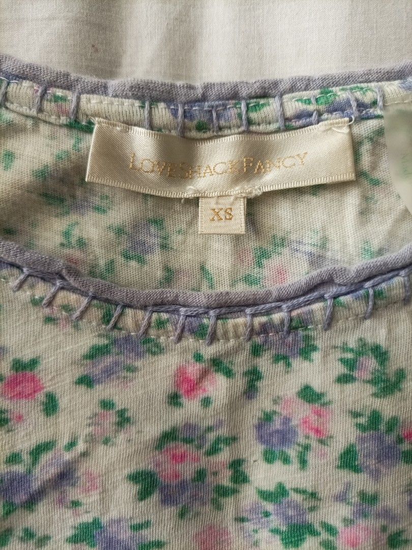 LoveShackFancy Floral Crop Top Size XS (Category: Sleeveless) located in Pasig City. Submitted by sandacecloset (Listing ID 1468788037, Image 3). Description: - Brand: LoveShackFancy - Size: XS - Material: 100% Cotton - Design: Pink, purple, and green floral print on off-white background - Details: Contrast purple whipstitching on neckline/arms, raw edge hem, sleeveless - Care: Hand wash cold - Condition: there are several small holes on the shir