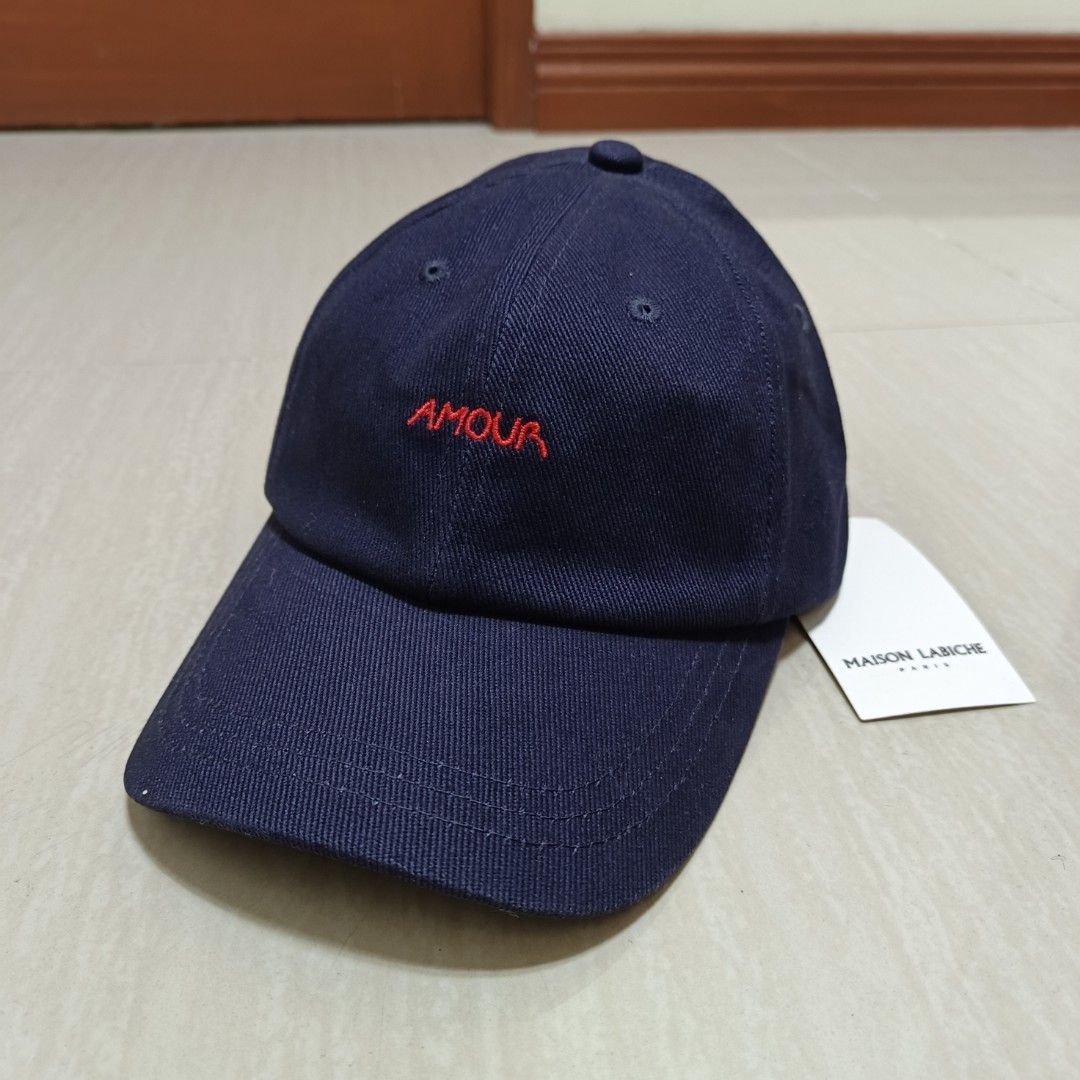 Maison Labiche Beaumont Amour Cap Carbon Blue (Category: Caps & Hats) located in Nasugbu. Submitted by staffpicks1515 (Listing ID 1468794682, Image 2). Description: - Brand: Maison Labiche - Color: Carbon blue with red 'AMOUR' embroidery - Material: 100% cotton - Size: Adjustable back strap with metal buckle - Condition: Brand new with original hangtags attached, never worn.