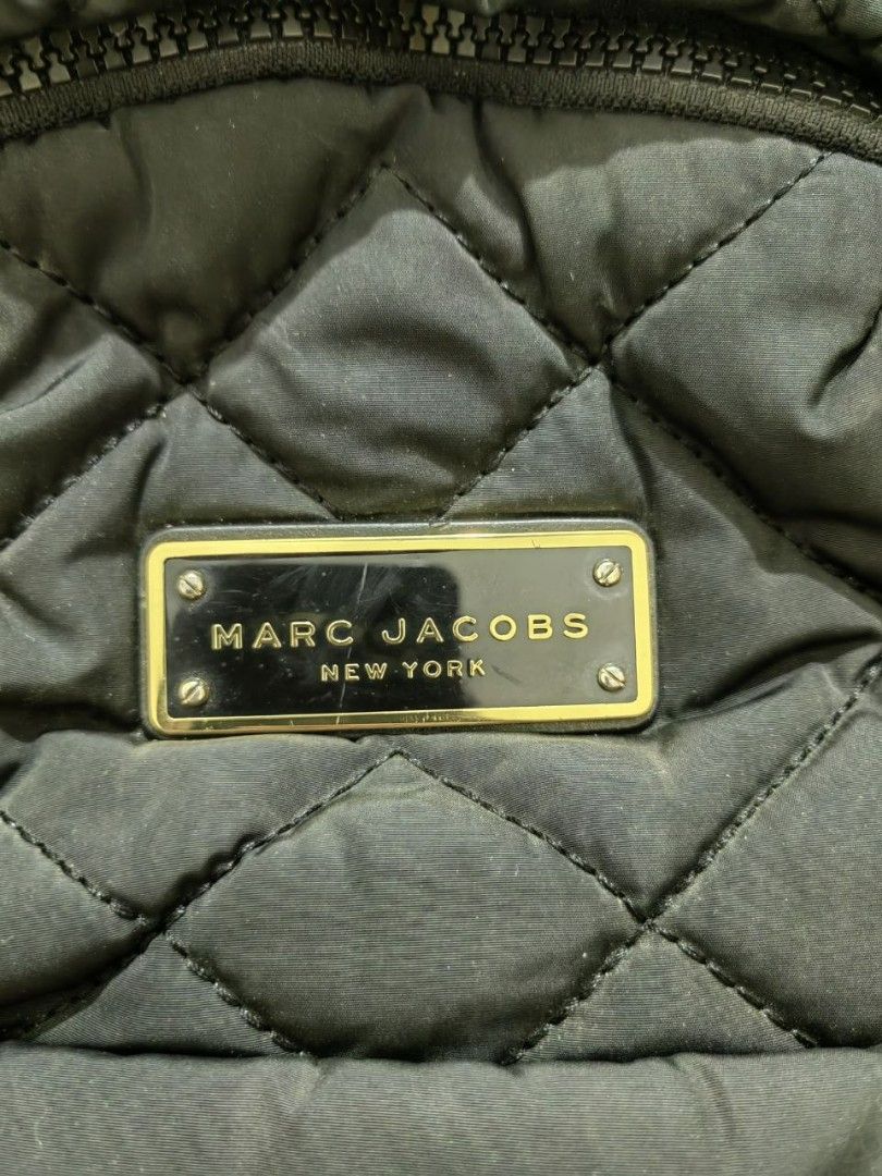 MARC JACOBS BLACK QUILTED NYLON BACKPACK (authentic) (Category: Luxury Bags & Wallets) located in Quezon City. Submitted by hirayacisum (Listing ID 1468748142, Image 2). Description: Material: Lightweight quilted nylon paired with leather zipper pulls and trim. Design: Classic dual-compartment layout including a roomy main body and a prominent zippered front pocket. Hardware: Polished gold-toned plaque stamped with "Marc Jacobs New York"..