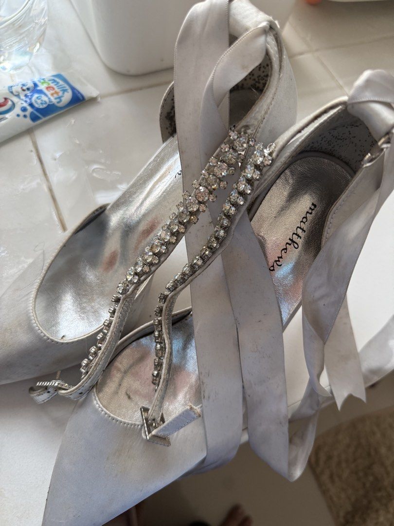 Matthews Silver Rhinestone Strappy Heels (Category: Heels) located in Manila. Submitted by maia_zsa (Listing ID 1468738294, Image 1). Description: - Brand: Matthews - Color: Silver - Style: Heels with rhinestone front strap and ribbon ankle ties - Flaws: Visible scuff marks and dirt on the satin fabric and insoles - Additional Notes: Interior heel lining has dark spots and staining - Perfect for budget-friendly glam nights!.