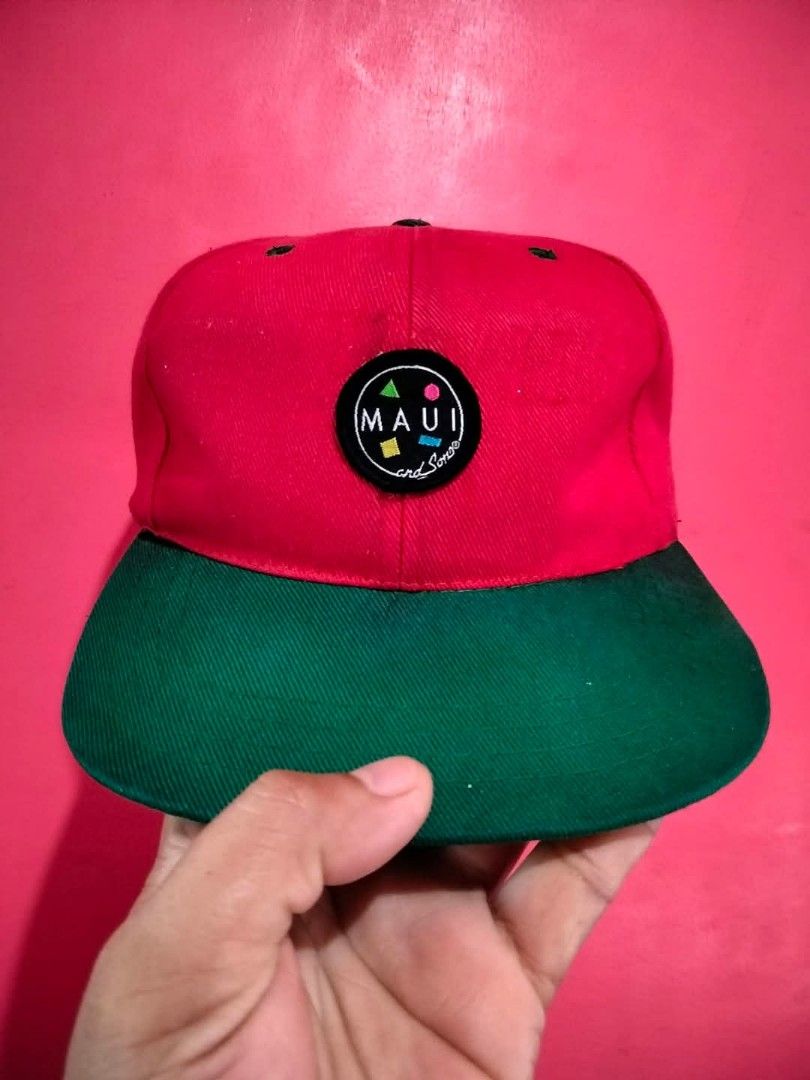 Maui and Sons Snapback Hat Red Green (Category: Caps & Hats) located in Mangaldan. Submitted by niftythrifty69 (Listing ID 1468734375, Image 1). Description: - Brand: Maui and Sons - Design: Round embroidered patch logo with colorful geometric shapes on the front - Colors: Vibrant red body with a contrast green flat brim - Fit: Adjustable snapback closure for a customized fit - Details: Interior features branded black taping and official tags - C