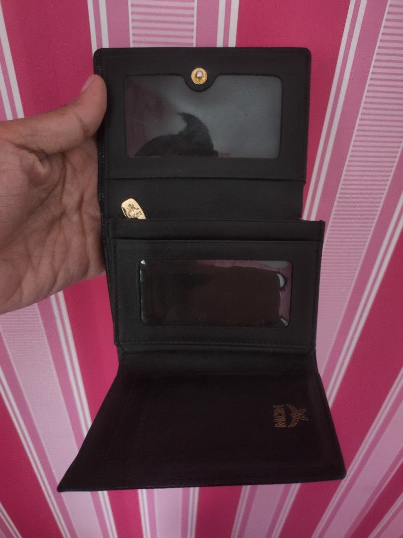 MCM Black Leather Trifold Wallet with Gold Hardware (Category: Luxury Bags & Wallets) located in Urdaneta. Submitted by assortedprelovedd (Listing ID 1468765324, Image 2). Description: - Brand: MCM - Material: Premium black textured leather - Hardware: Elegant gold-toned accents - Closure: Secure snap button - Interior: Clean lining with MCM stamped logo - Compartments: Multiple card slots, ID window pockets, and a full-length cash compartment - 