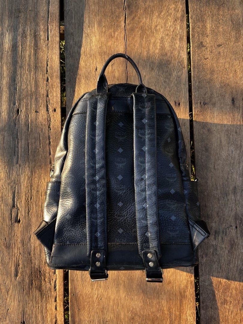 MCM Stark Studded Backpack Black Visetos Coated Canvas (Category: Backpacks) located in Mapandan. Submitted by thriftyfits.670 (Listing ID 1468927030, Image 2). Description: - Brand: MCM - Material: Visetos coated canvas in classic black with dark grey monogram - Hardware: Silver-tone and gold-tone metal pyramid studs, iconic brass logo plate - Pockets: Classic front zip pocket, two side slip pockets, and roomy interior - Straps: Top handle and a