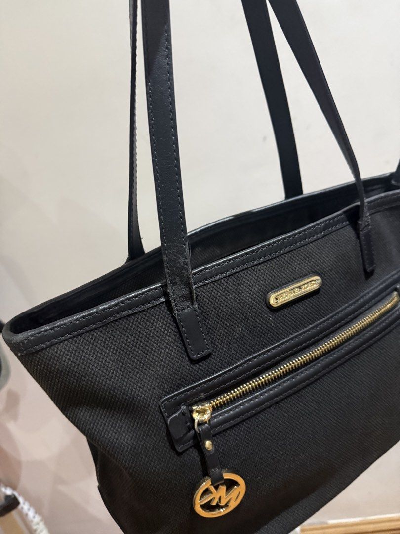 Michael Kors Black Tote Bag With Front Zipper (Category: Tote Bags) located in Manila. Submitted by mpt99876 (Listing ID 1468853405, Image 2). Description: - Authentic Michael Kors black tote bag - Textured fabric body with premium leather handles and trim - Elegant gold-tone hardware with front zipper pocket and MK logo charm - Secure top zip closure - Spacious lined interior, easily fits books or a small laptop - Stuffed properly to maintain it